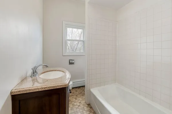 a bathroom with a granite countertop sink and a bathtub
