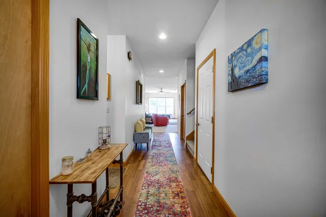 a hallway with painting on the wall and a wooden floor