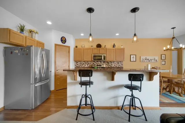 a kitchen with stainless steel appliances kitchen island granite countertop a table chairs and a refrigerator