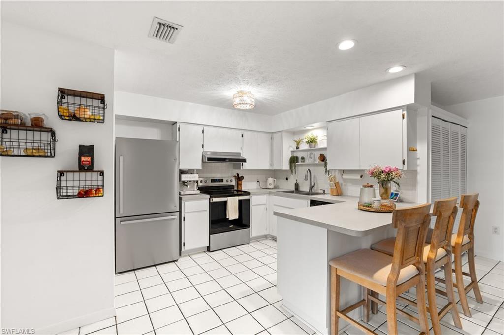 1030 13th Street Southwest Naples, FL 34117 - Photo 14 of 43 a kitchen with stainless steel appliances a refrigerator stove microwave and cabinets