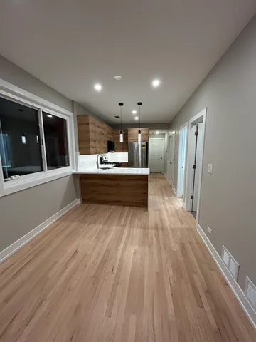 a large white kitchen with wooden floors and stainless steel appliances