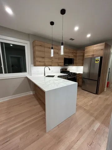 a kitchen with stainless steel appliances granite countertop a sink a stove and a wooden floors