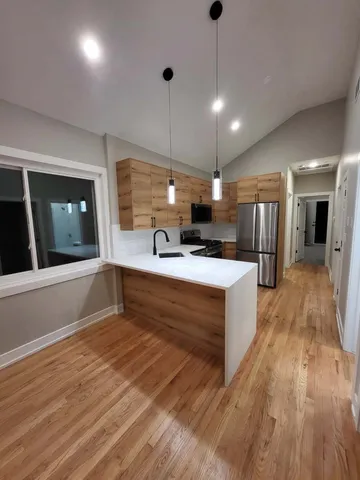 a large kitchen with stainless steel appliances kitchen island a large counter space a sink and a fireplace