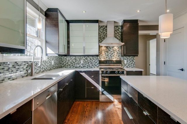 a kitchen with stainless steel appliances granite countertop a refrigerator a sink dishwasher a stove and white countertops with wooden floor