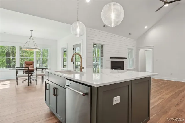 a living room with kitchen island granite countertop wooden floor and a sink
