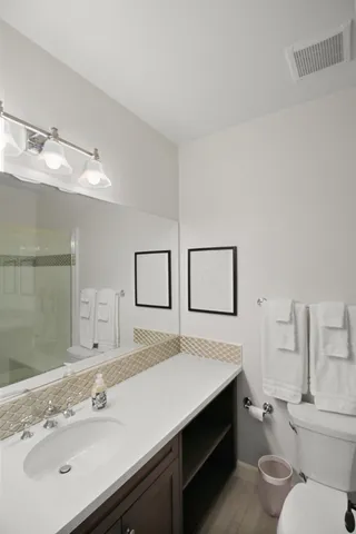 a bathroom with a sink mirror vanity and toilet