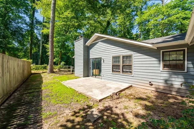 a view of house with backyard and trees in the background