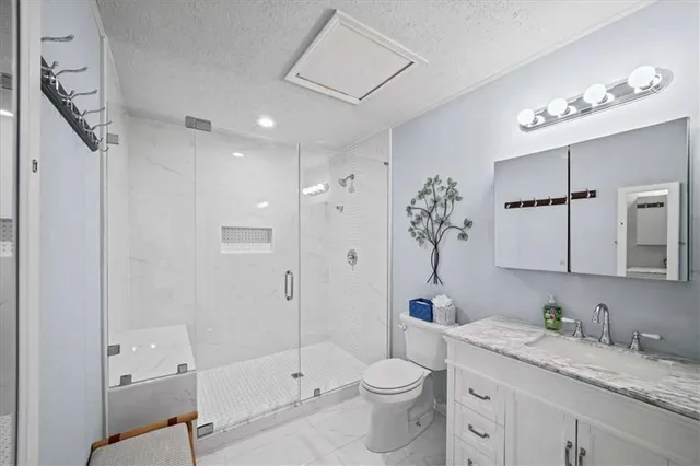 a bathroom with a granite countertop sink a toilet a large mirror and shower