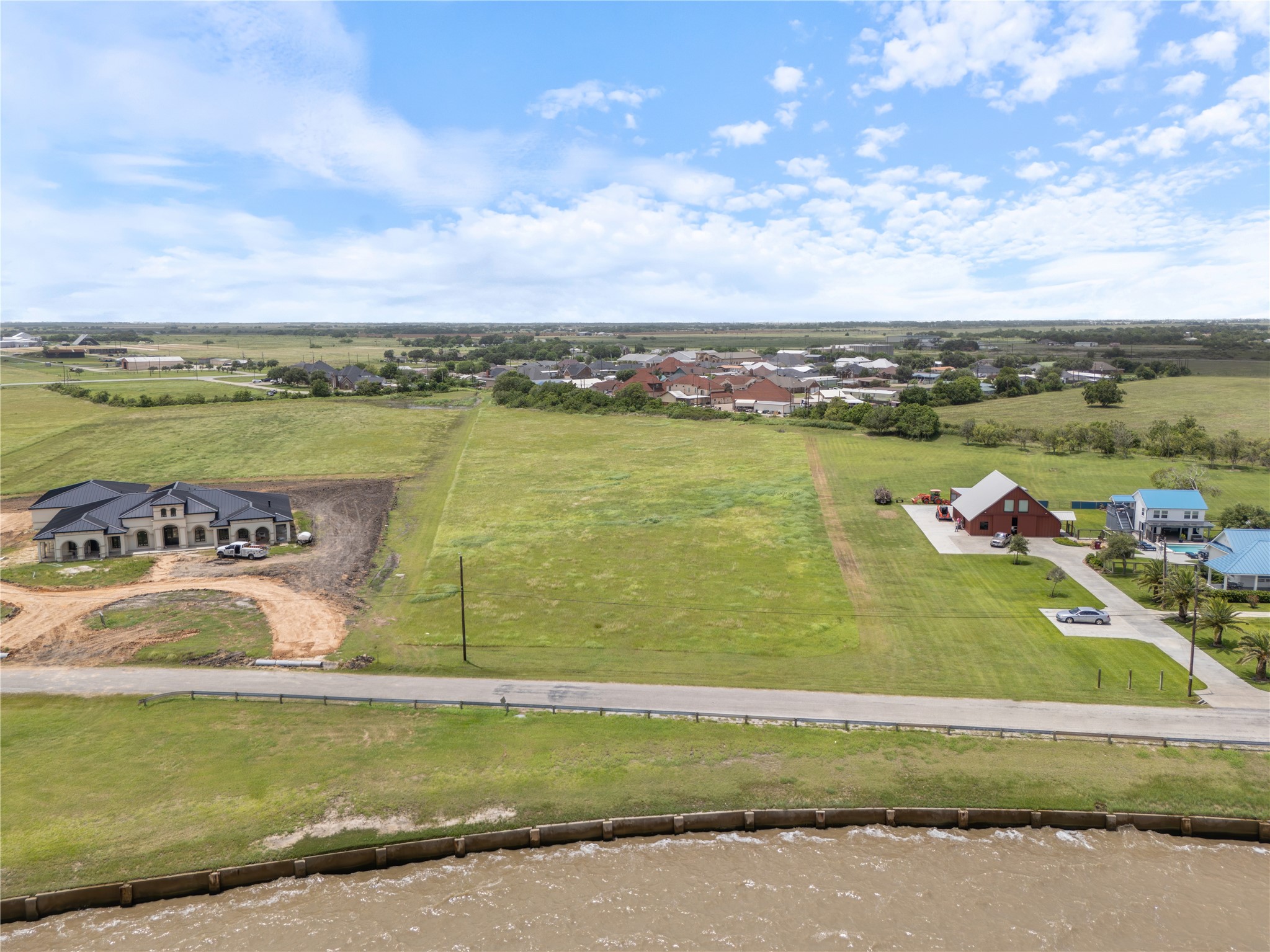 305 Bayshore Road Palacios, TX 77465 - Photo 11 of 25 A sweeping aerial perspective reveals an expansive, ready-to-build lot nestled between a water view and distant residential areas.