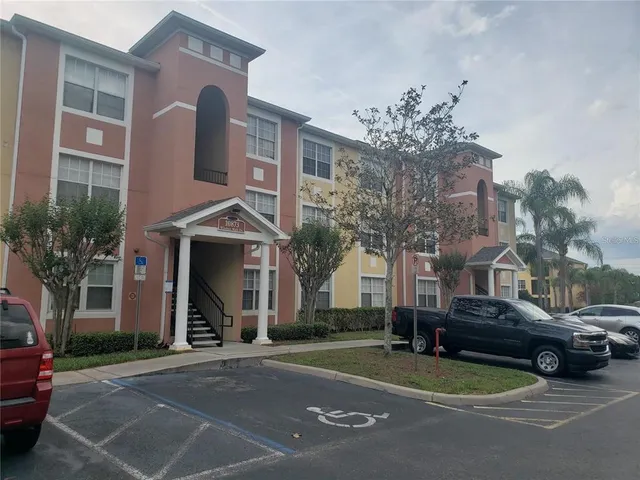 a front view of a building with lot of cars and trees