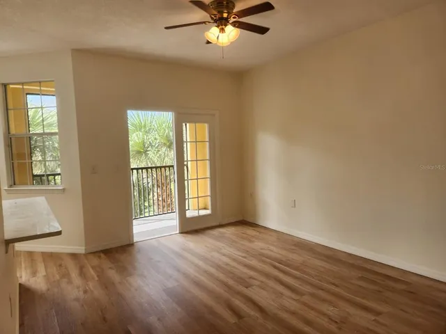a view of an empty room with wooden floor and a window