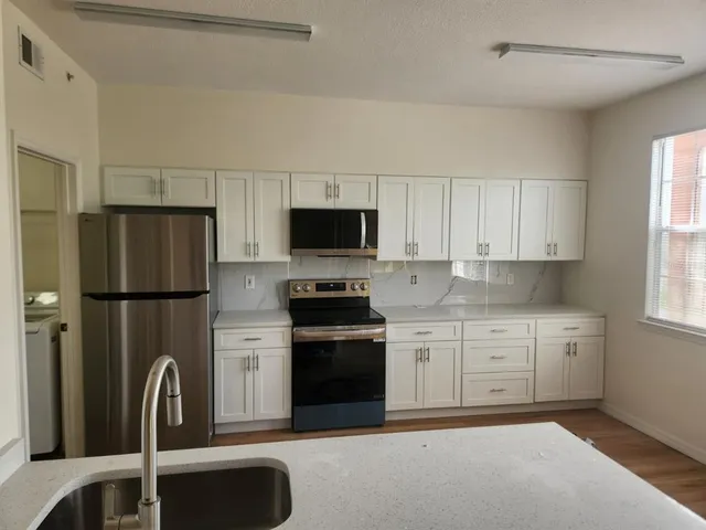 a kitchen with stainless steel appliances granite countertop a refrigerator sink and stove