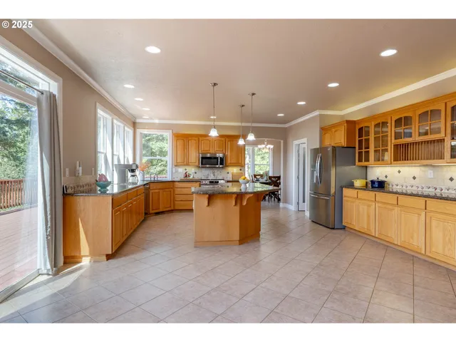 a kitchen with stainless steel appliances kitchen island granite countertop a stove a sink a refrigerator with white cabinets and couches