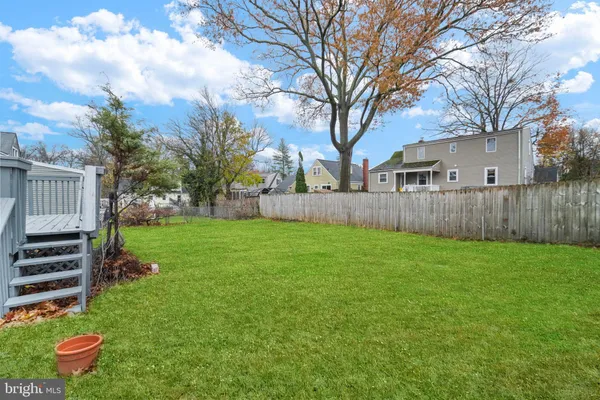 a view of a backyard with large trees and wooden fence