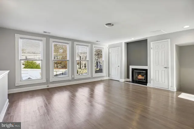 an empty room with wooden floor fireplace and windows