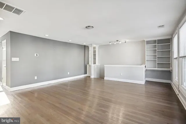 a view of an empty room with a window and wooden floor