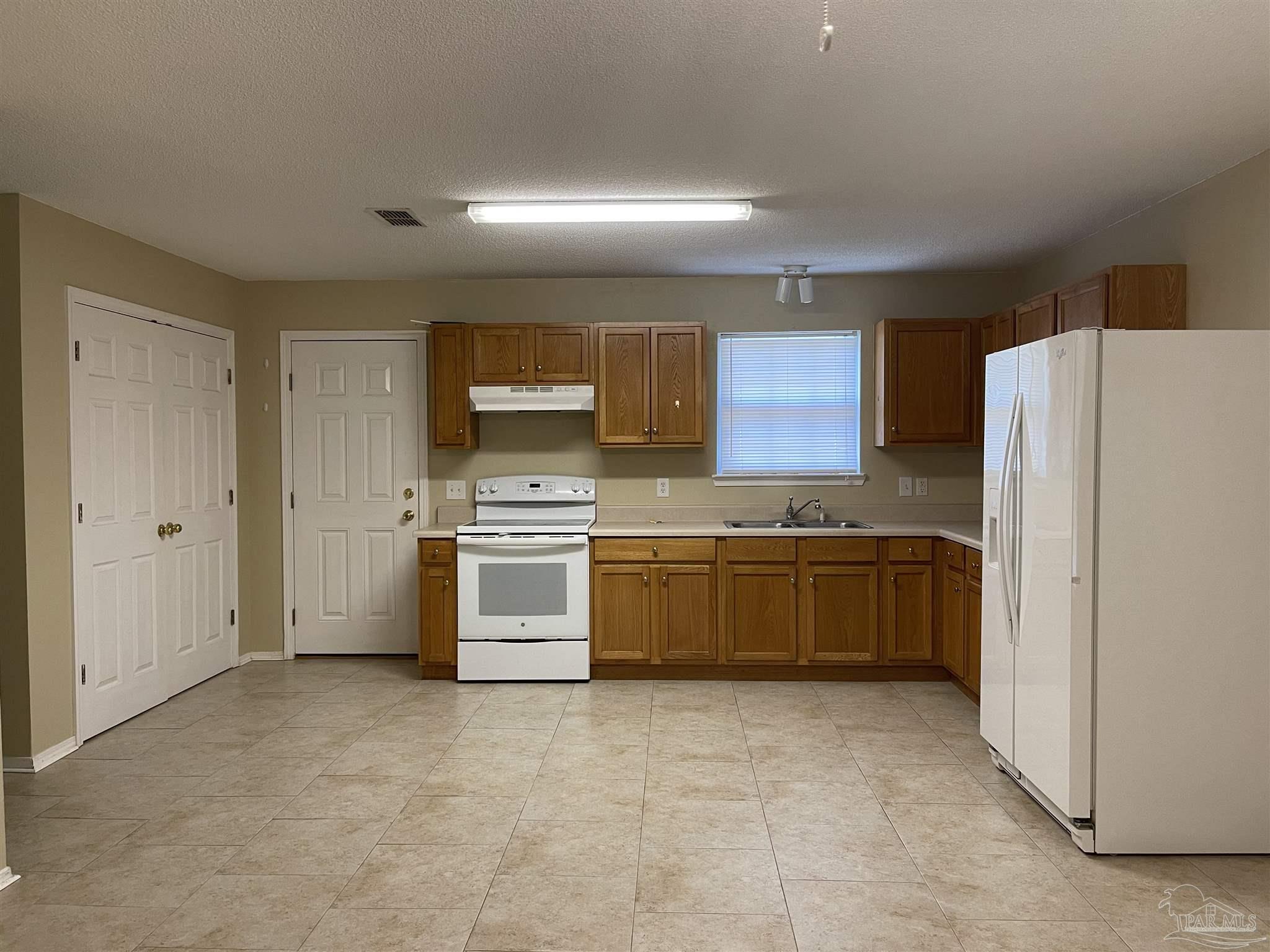 6208 St Ann Avenue Milton, FL 32570 - Photo 6 of 20 a kitchen with a refrigerator and a stove top oven