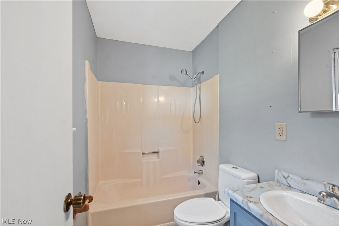 1286 Deforest Road Southeast Warren, OH 44484 - Photo 9 of 27 Bathroom featuring a shower-tub combination with a white surround, a toilet, and a vanity with a countertop and integrated sink