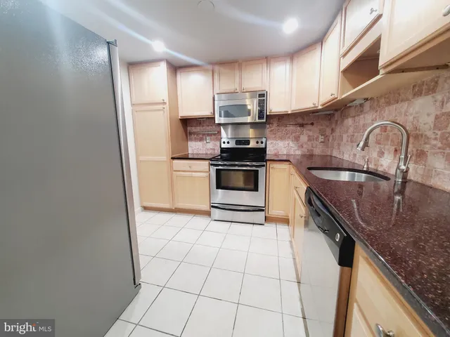 a kitchen with a sink a stove top oven and cabinetry