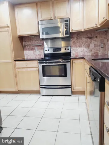 a kitchen with granite countertop a stove a sink and a white cabinets