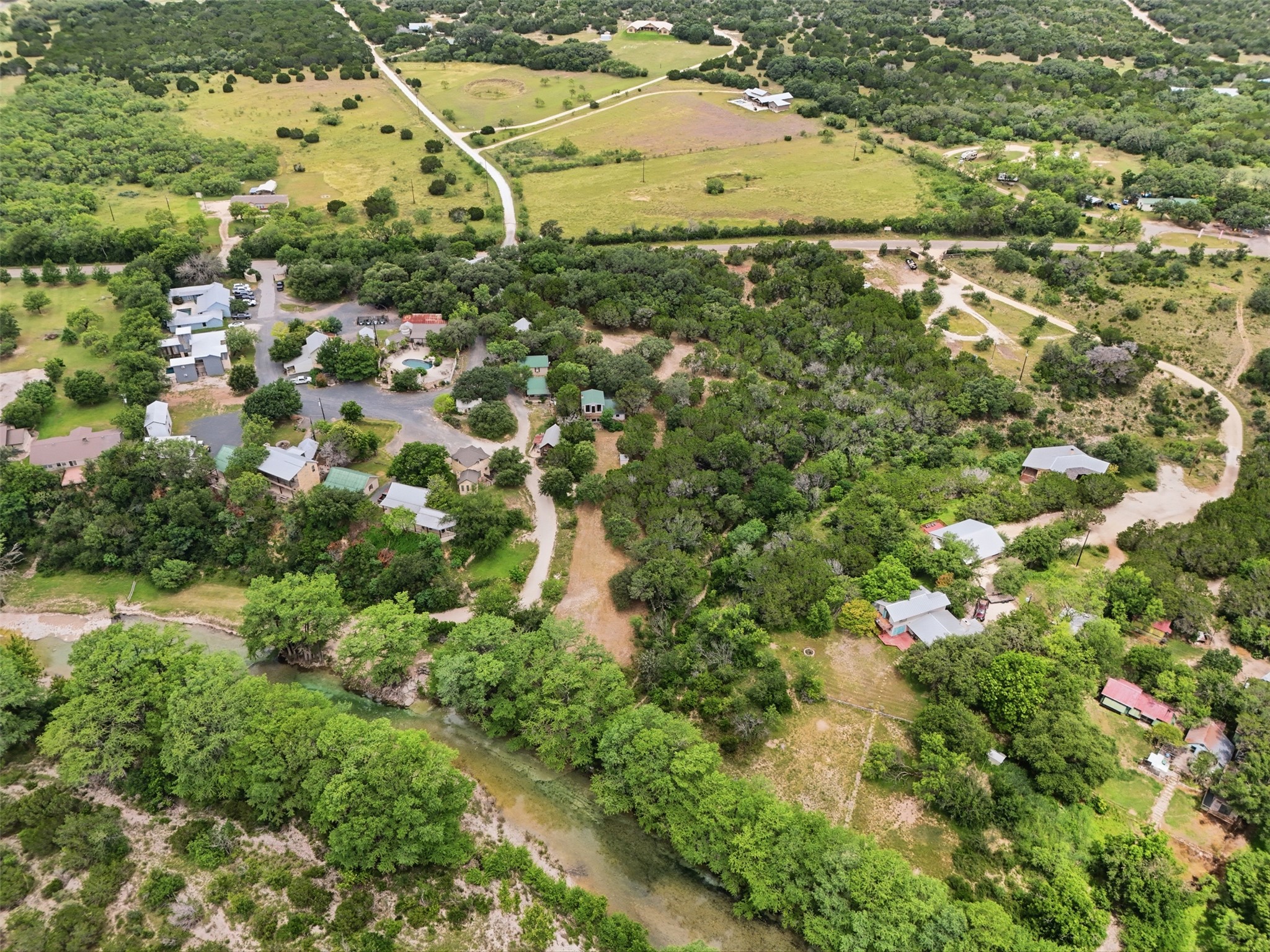 1260 Magers Road Concan, TX 78838 - Photo 38 of 40 An aerial perspective reveals a verdant landscape with homes nestled along a winding river and surrounding natural acreage.