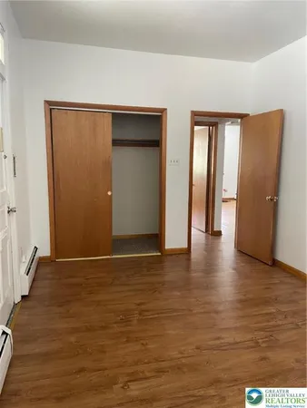 a view of an empty room with wooden floor and closet
