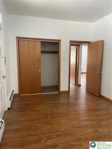 a view of an empty room with wooden floor and closet