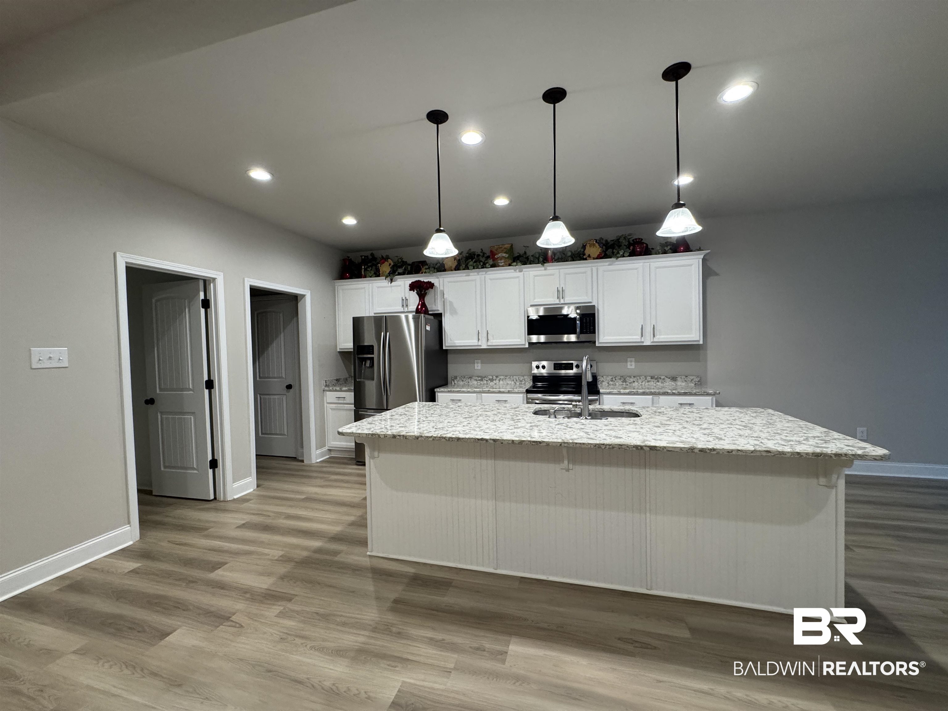 1060 Chloe Street Foley, AL 36535 - Photo 10 of 28 Open-concept kitchen featuring an oversized island with beadboard paneling, recessed lighting, pendant lights, wood-finish flooring, and stainless steel appliances