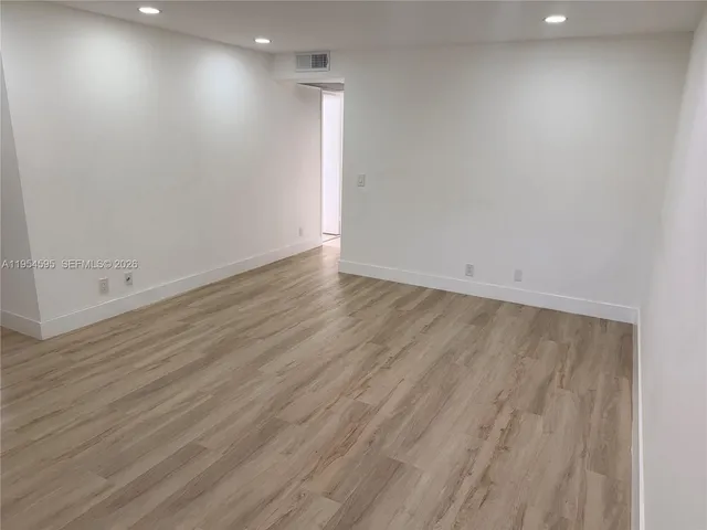 an empty room with wooden floor and white walls