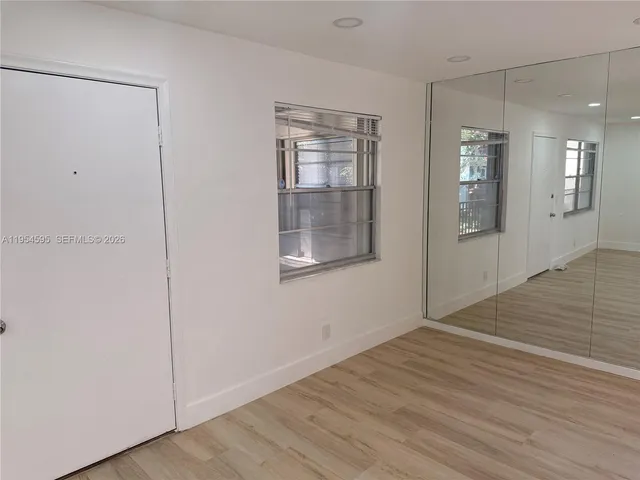 a view of an empty room with wooden floor and a bathroom