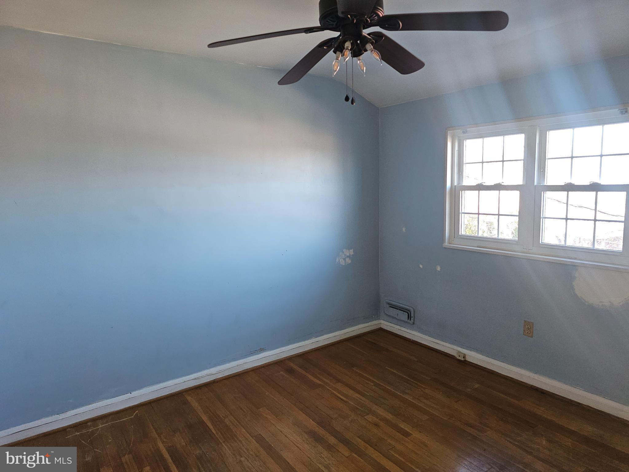4728 Williston Street Baltimore, MD 21229 - Photo 6 of 17 an empty room with wooden floor fan and windows