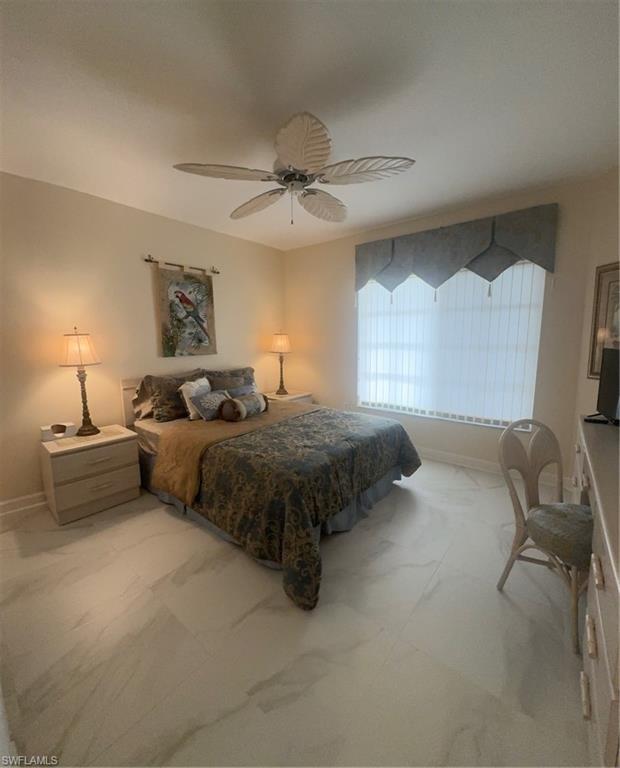 13105 Vanderbilt Drive, Unit 808 Naples, FL 34110 - Photo 19 of 26 a spacious bedroom with a bed a chandelier and a couch