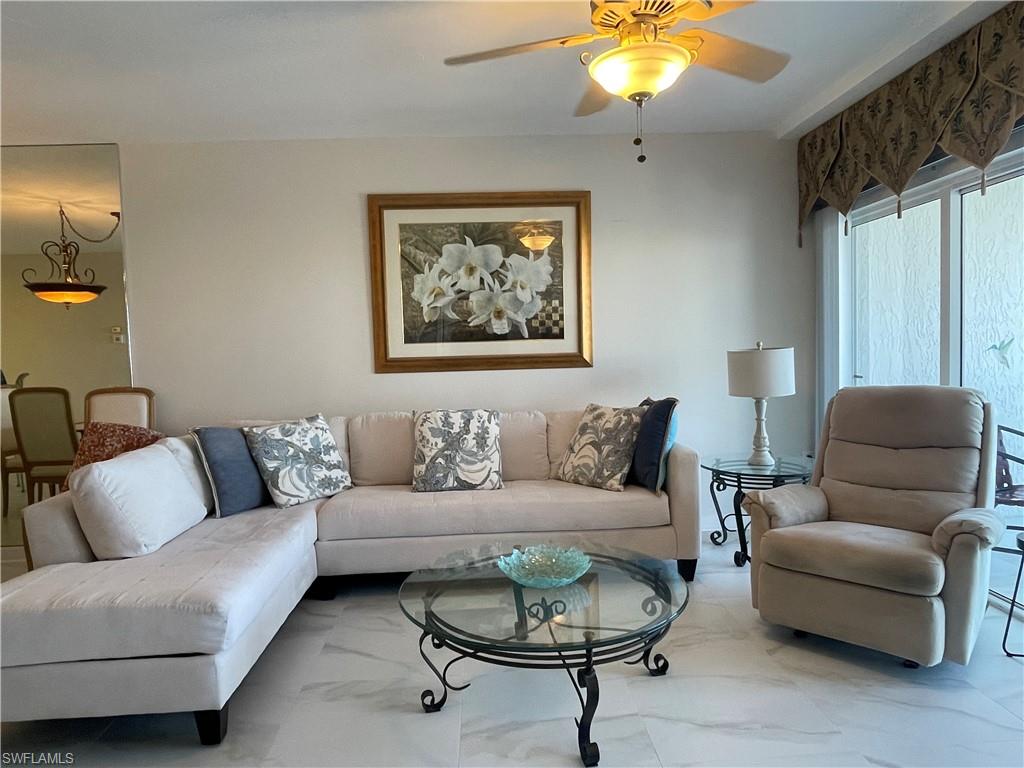 13105 Vanderbilt Drive, Unit 808 Naples, FL 34110 - Photo 4 of 26 a living room with furniture and a chandelier