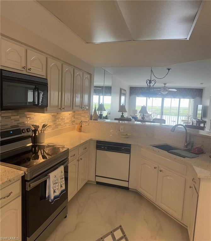 13105 Vanderbilt Drive, Unit 808 Naples, FL 34110 - Photo 10 of 26 a kitchen with granite countertop a stove sink and microwave