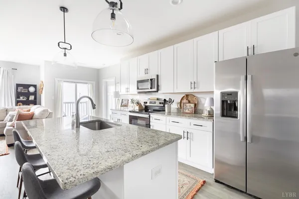 a kitchen with granite countertop a refrigerator a stove a sink a dining table and chairs
