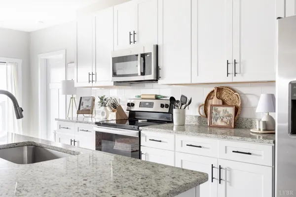 a kitchen with granite countertop a stove a sink and a microwave