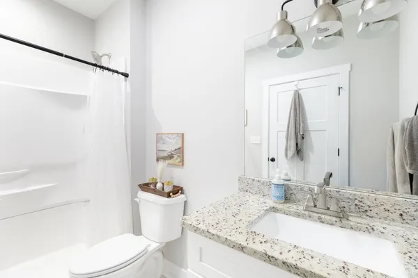 a bathroom with a granite countertop toilet sink and mirror