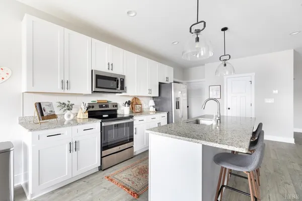 a kitchen with a stove a sink a microwave a refrigerator a counter space and cabinets