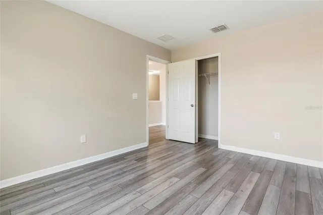 a view of an empty room with wooden floor and closet