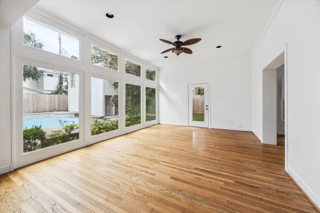 a view of an empty room with a window and wooden floor