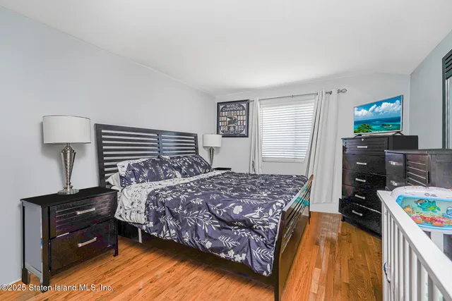 a bedroom with a bed and a flat tv screen on dresser