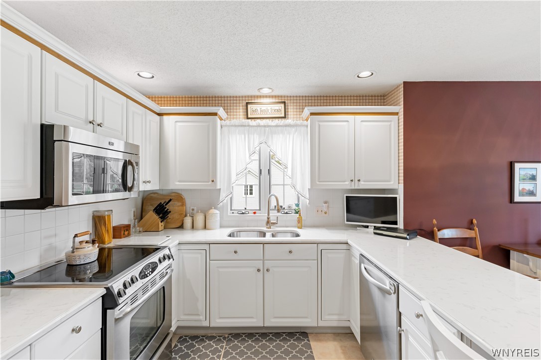 2850 Amsdell Road, Unit 34 Hamburg, NY 14075 - Photo 4 of 33 Crisp white cabinetry paired with modern stainless steel appliances creates an efficient, inviting workspace.