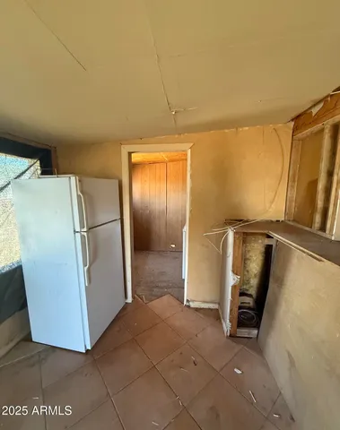 a view of a refrigerator in kitchen and an empty room