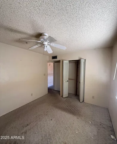 an empty room with a ceiling fan and closet