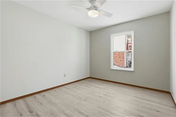 an empty room with wooden floor chandelier fan and windows
