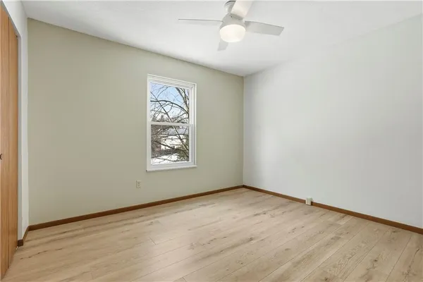 an empty room with wooden floor chandelier fan and windows
