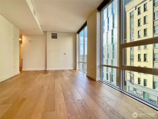 a view of a big room with wooden floor and windows