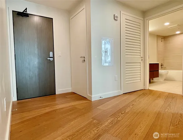 a view of an empty room with wooden floor and a bathroom