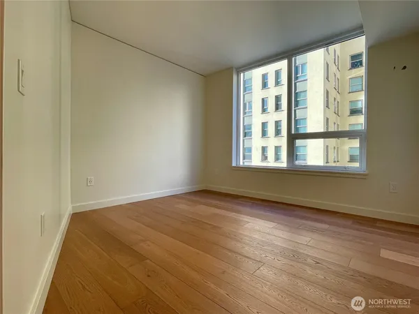 a view of an empty room with wooden floor and a window