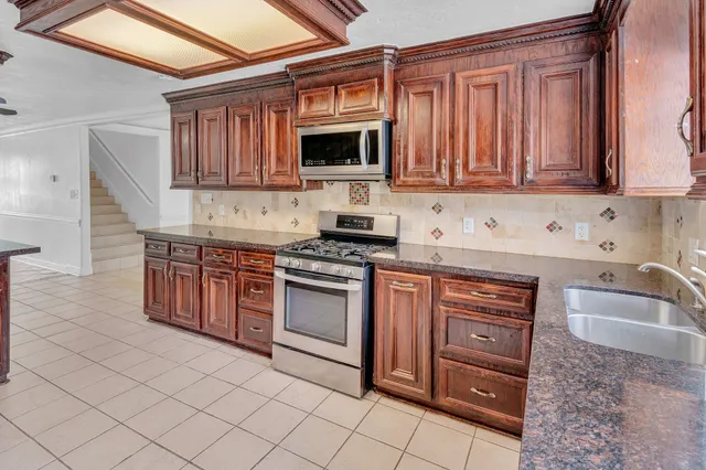 a kitchen with stainless steel appliances granite countertop a stove a sink and a microwave